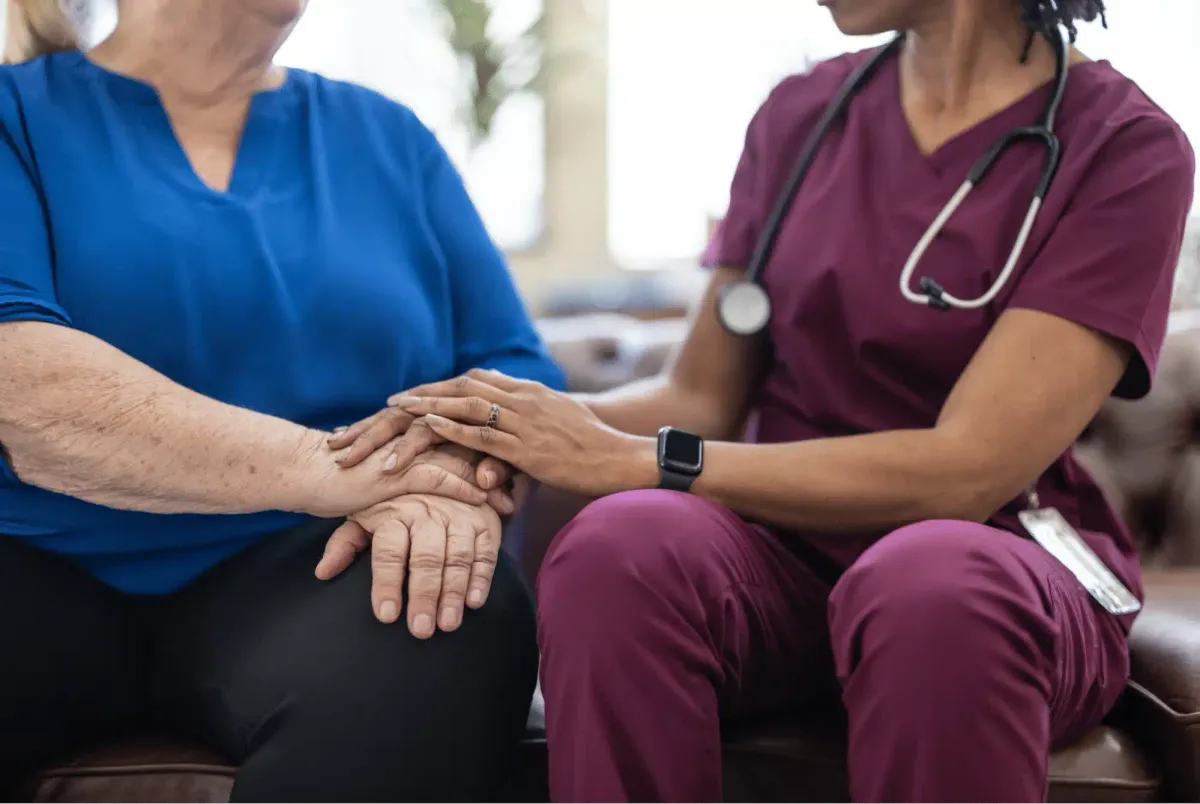 A hospice nurse comforting a patient by holding her hands