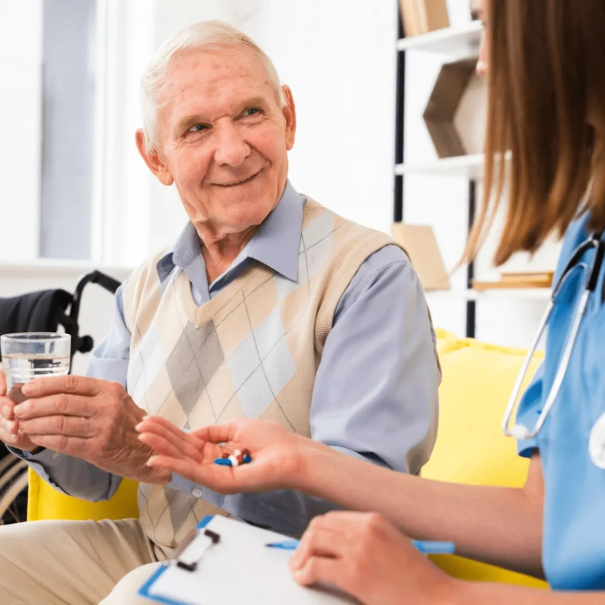 A hospice nurse handing an older patient his medication at home